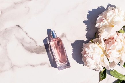 an-elegant-perfume-bottle-with-a-delicate-fragrance-of-spring-flowers-on-a-white-marble-background-with-peonies-aroma-presentation-top-view