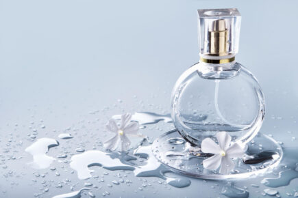 glass-perfume-bottle-drops-water-and-white-flowers-on-blue-background-winter-or-spring-floral-fragrance-435x290